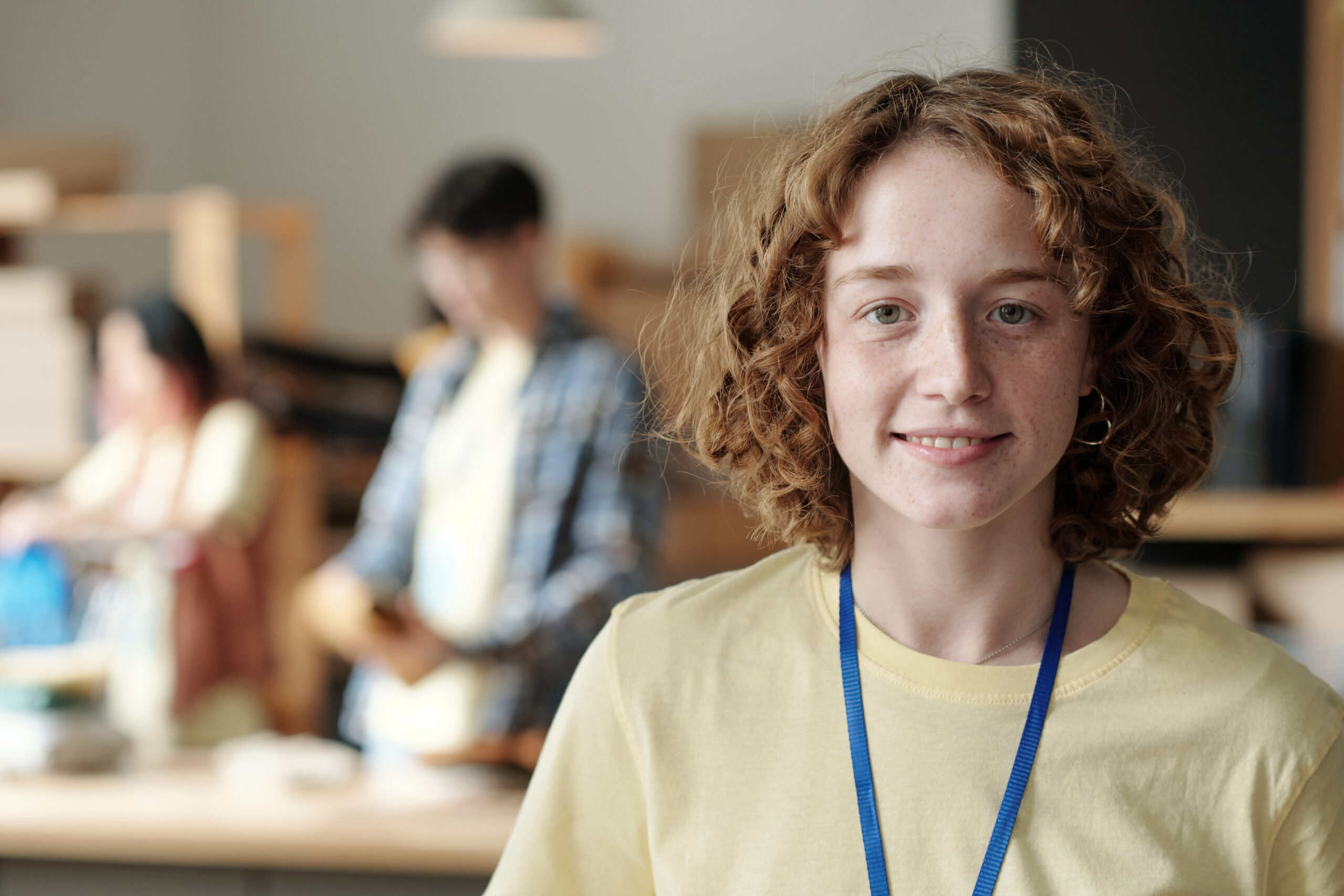 Joven con cabello rizado sonriendo en un entorno de oficina desenfocado.